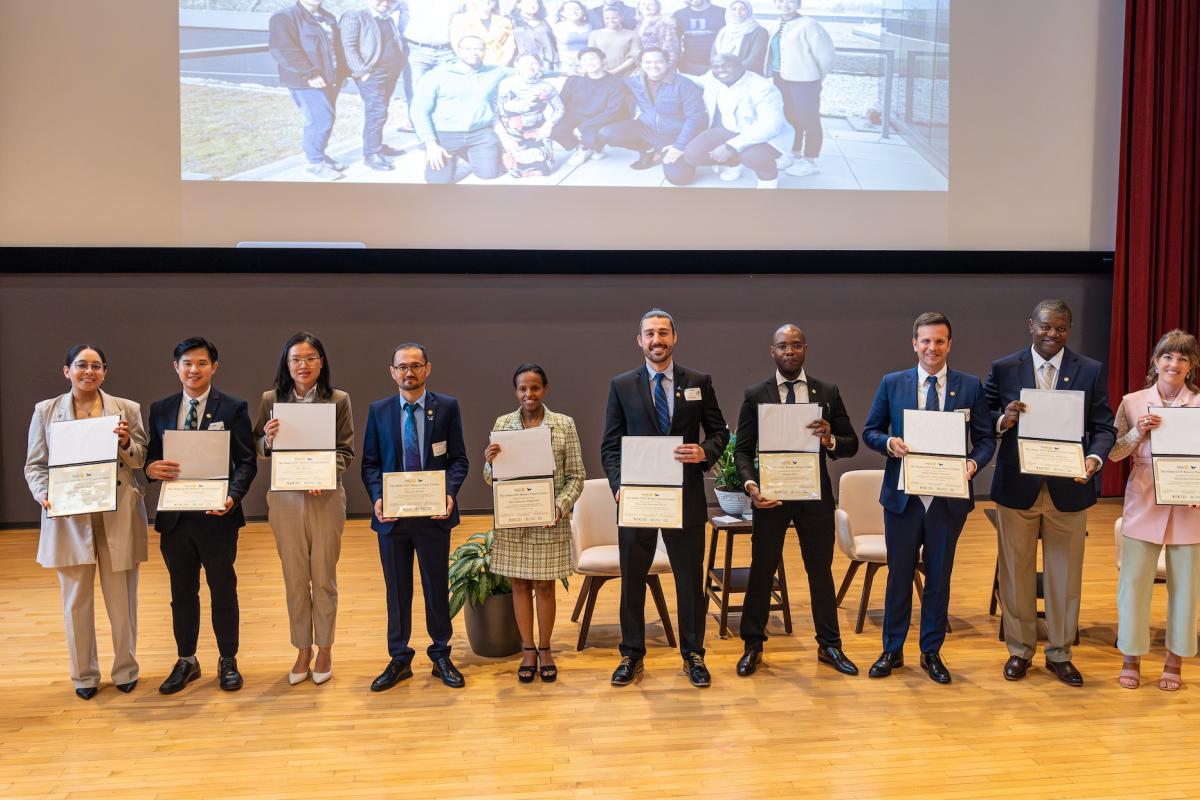 Ten people standing on a stage and each is holding a paper certificate.