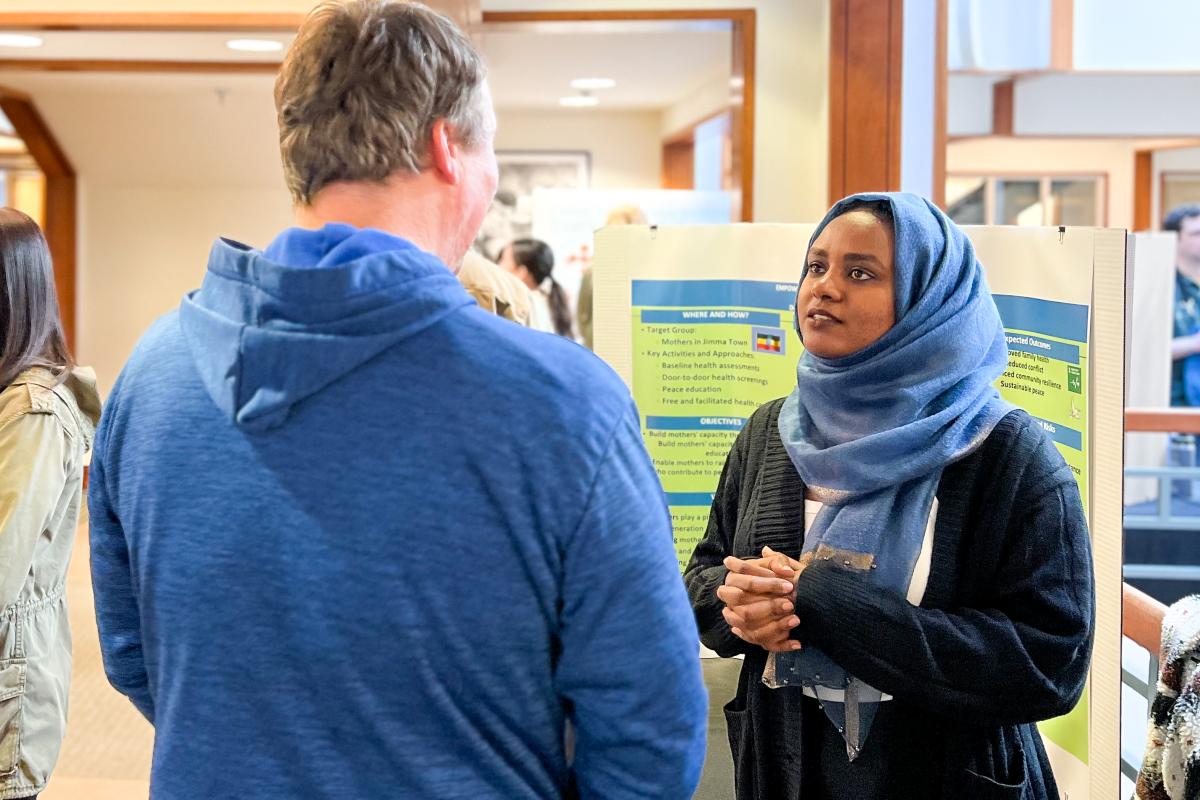 Two people speaking while standing in front of a poster