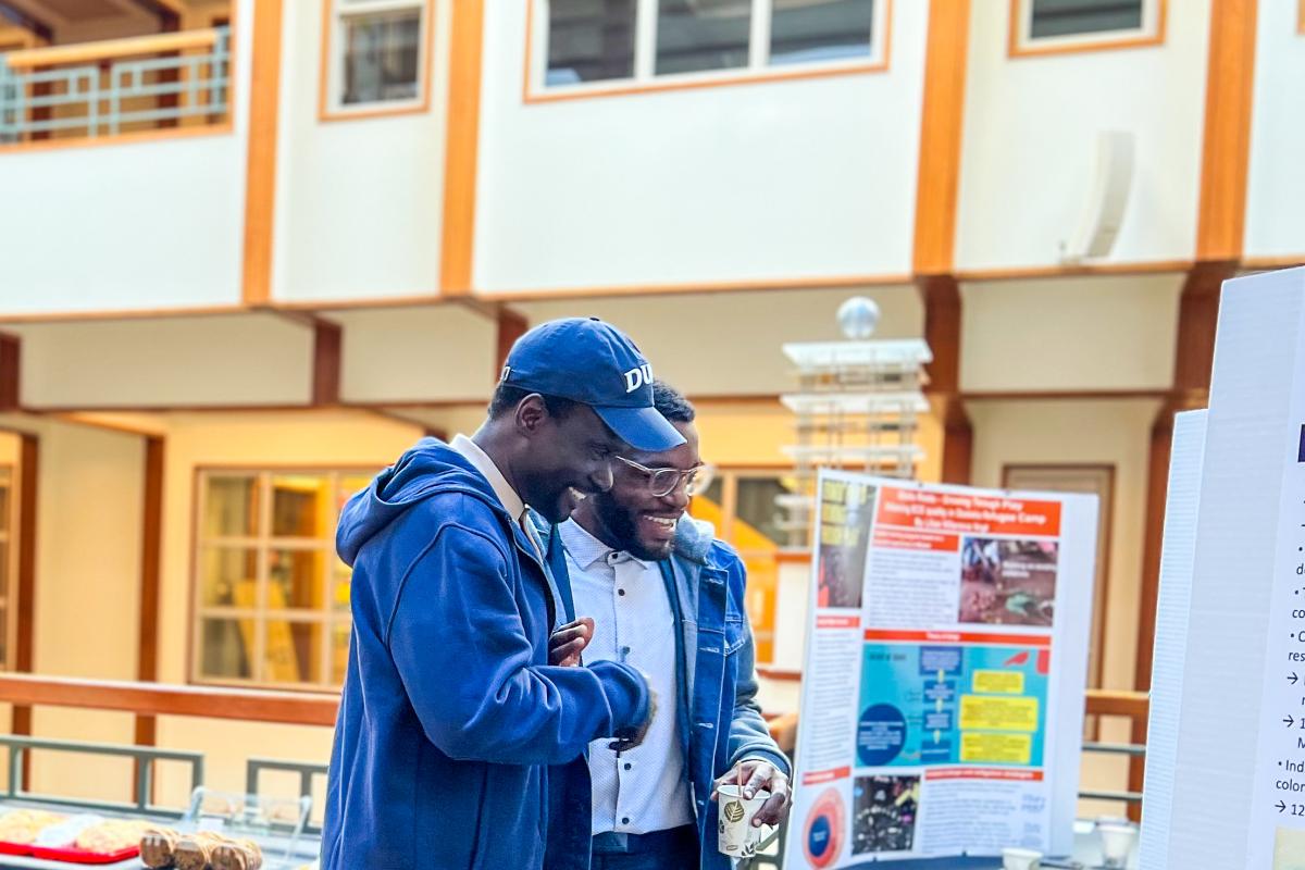 Two people speaking while looking at a poster.