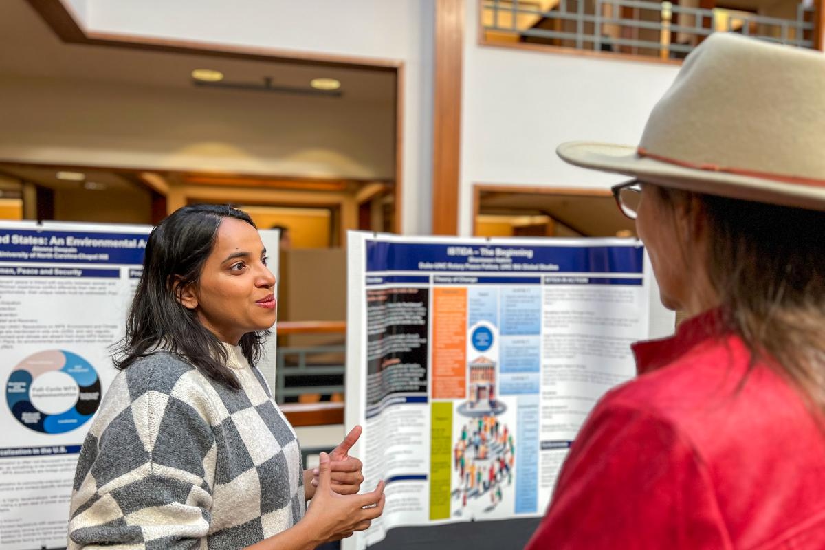 Two people talking while standing in front of a poster